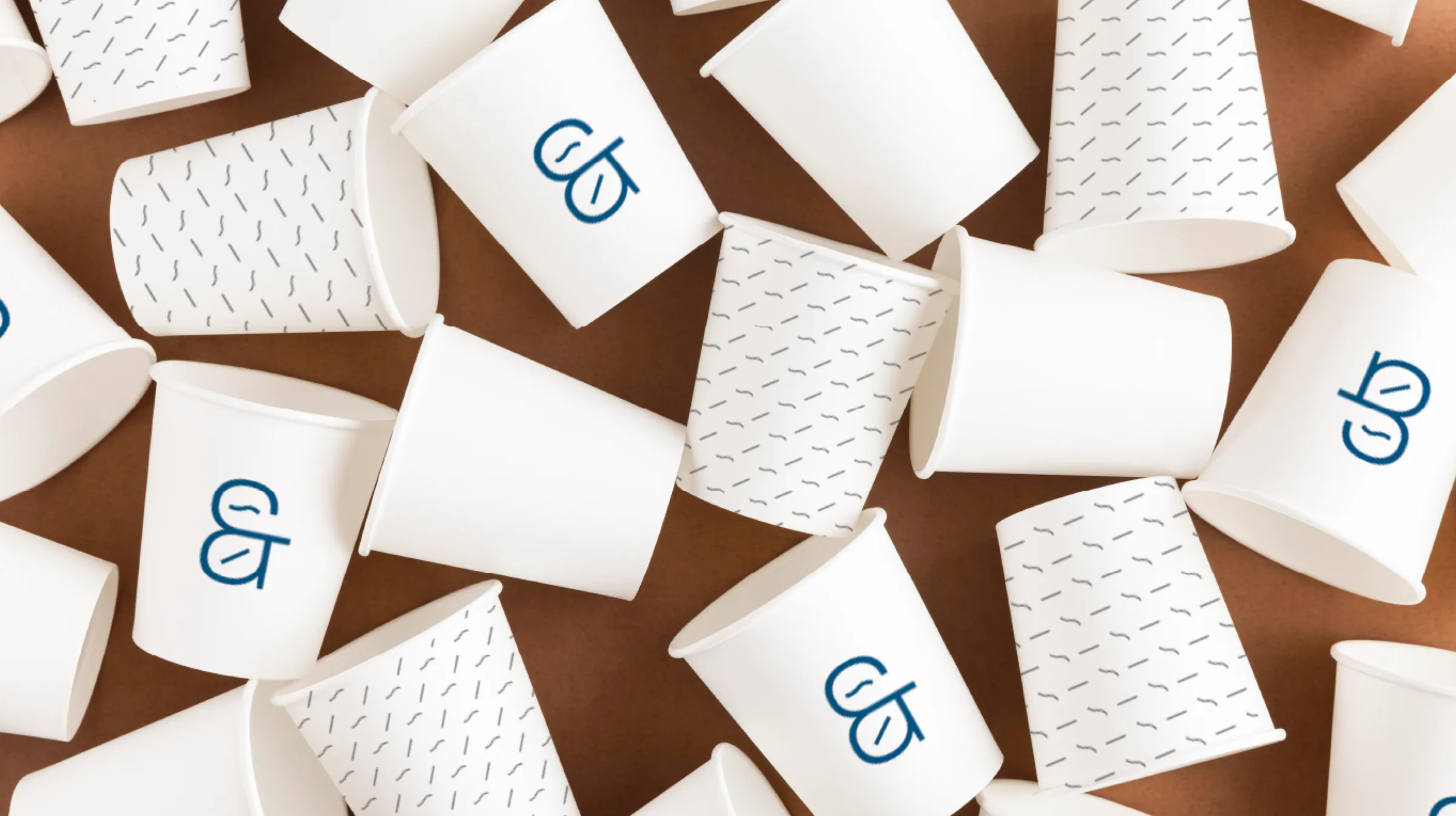 White paper cups with the ampersand and stroke pattern on a brown table